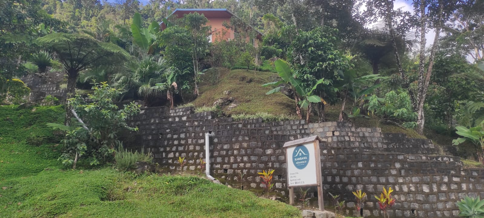 un panneau vert au bord de la route contenant le logo du Kambana Résidence